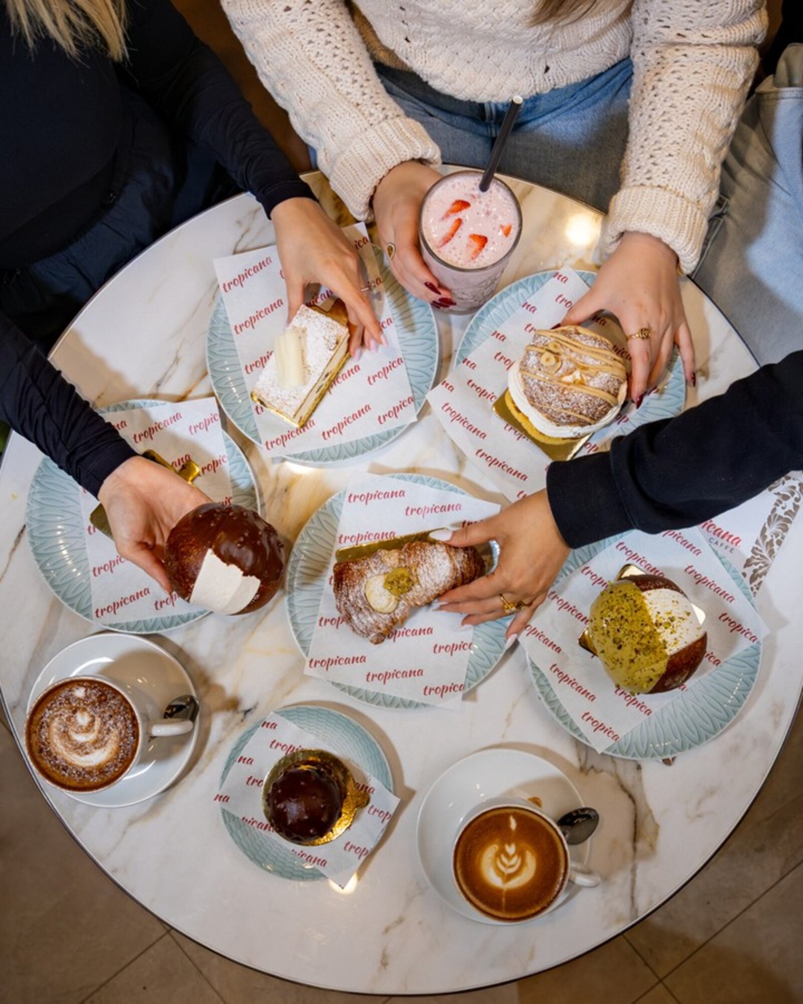A Tropicana share table with pastries, coffee and an Aperol spritz